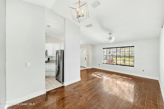 unfurnished living room with a chandelier, light hardwood / wood-style floors, and lofted ceiling