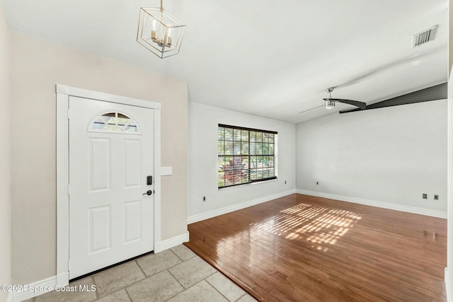 entryway with ceiling fan with notable chandelier and light hardwood / wood-style floors