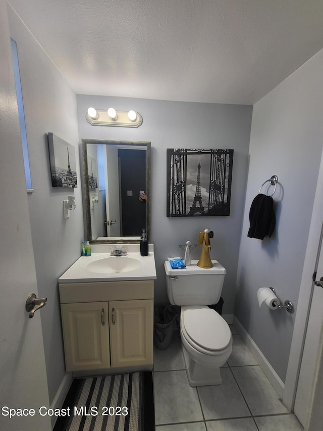 bathroom with tile patterned flooring, vanity, a textured ceiling, and toilet