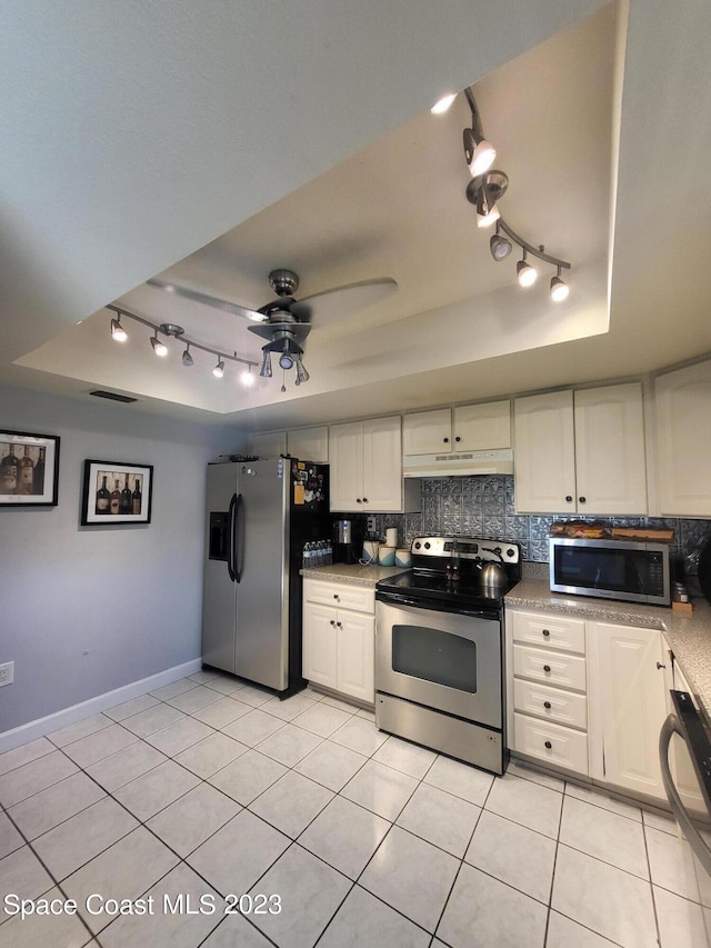 kitchen featuring white cabinetry, appliances with stainless steel finishes, a tray ceiling, and decorative backsplash