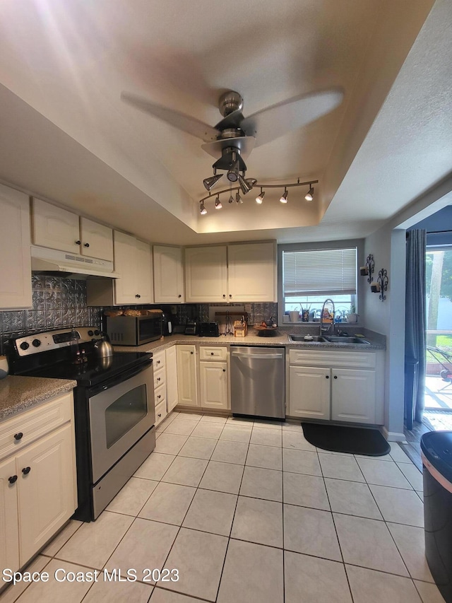 kitchen with sink, white cabinets, backsplash, light tile patterned floors, and stainless steel appliances