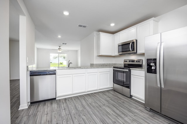 kitchen featuring white cabinets, light wood-type flooring, appliances with stainless steel finishes, and sink