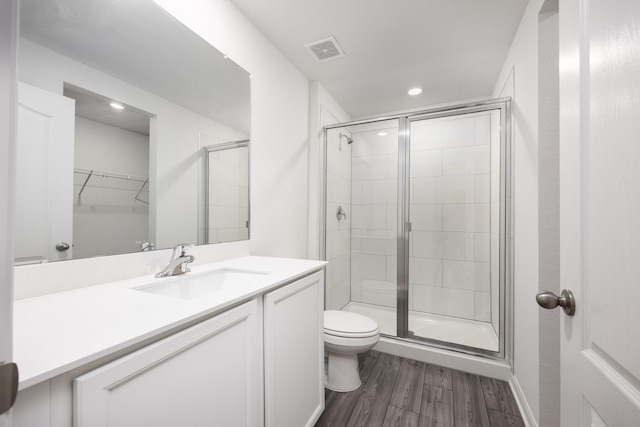 bathroom featuring vanity, walk in shower, hardwood / wood-style floors, and toilet