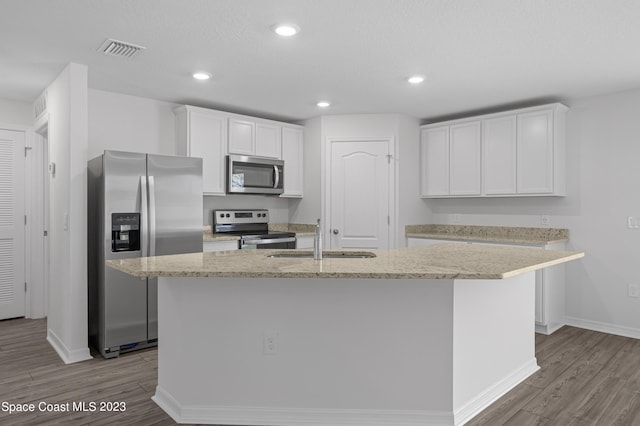 kitchen with stainless steel appliances, an island with sink, sink, and white cabinetry