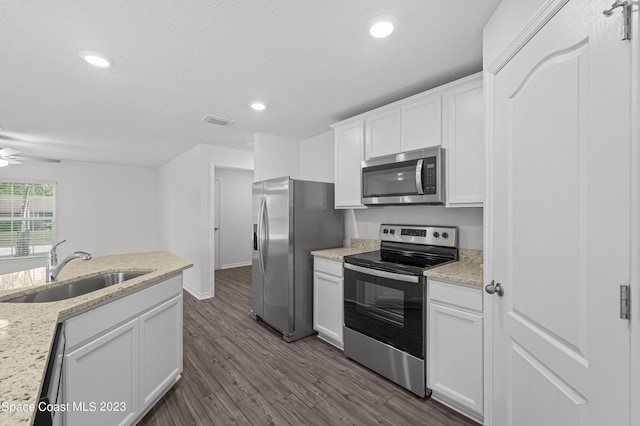 kitchen with stainless steel appliances, white cabinetry, sink, and light stone counters