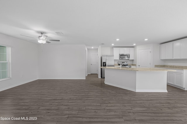 kitchen with white cabinetry, appliances with stainless steel finishes, dark hardwood / wood-style flooring, and a kitchen island with sink