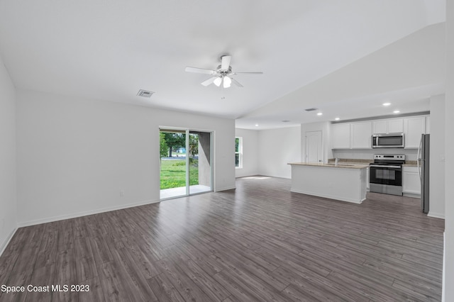 unfurnished living room featuring lofted ceiling, sink, dark wood-type flooring, and ceiling fan