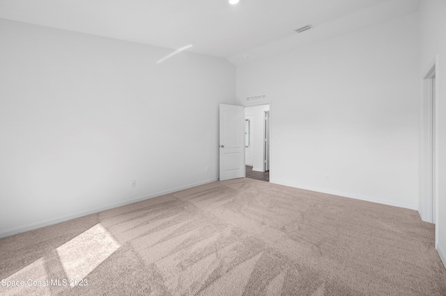 empty room with carpet and high vaulted ceiling