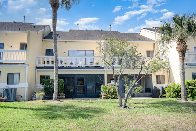 rear view of property featuring a balcony, central AC unit, and a lawn