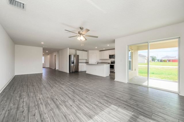 unfurnished living room with sink, a textured ceiling, ceiling fan, and hardwood / wood-style floors