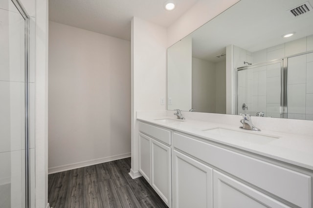 bathroom with an enclosed shower, hardwood / wood-style flooring, and dual bowl vanity