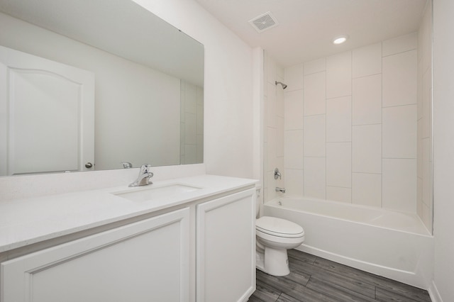 full bathroom featuring tiled shower / bath combo, large vanity, toilet, and hardwood / wood-style floors