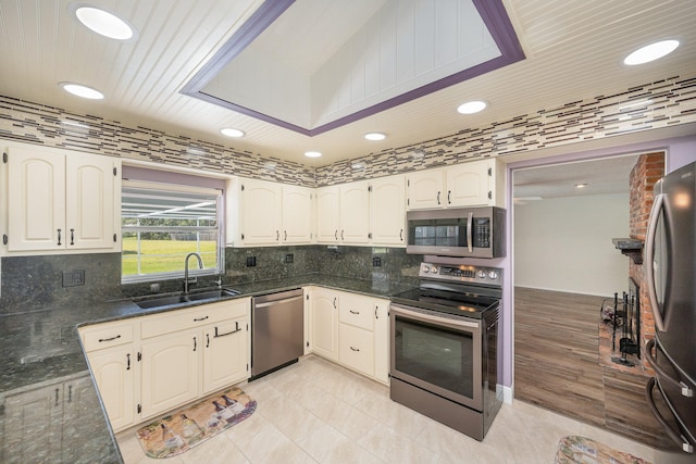 kitchen with stainless steel appliances, white cabinets, sink, tasteful backsplash, and light tile flooring