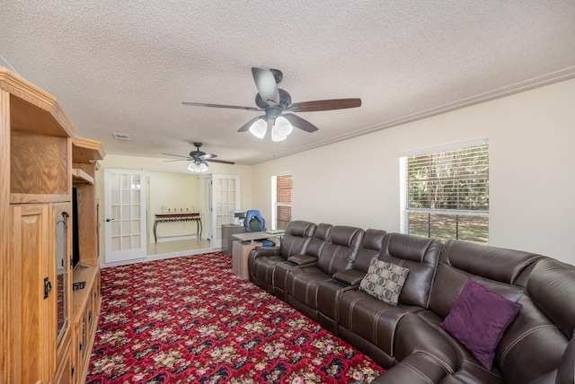 living room with carpet, ceiling fan, french doors, and a textured ceiling