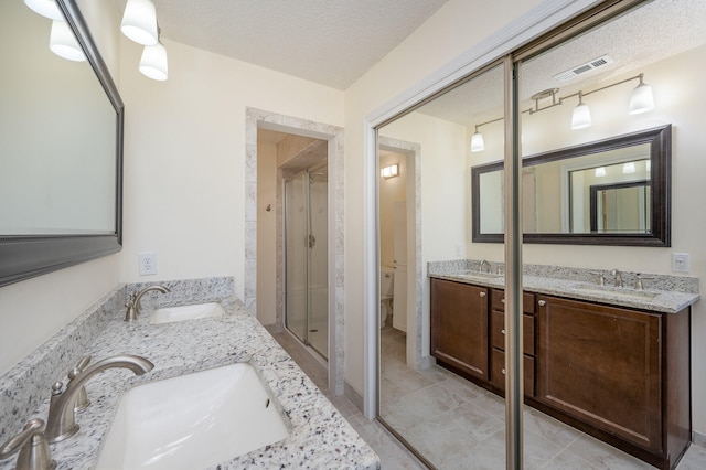 bathroom featuring tile floors, a textured ceiling, a shower with shower door, and dual bowl vanity