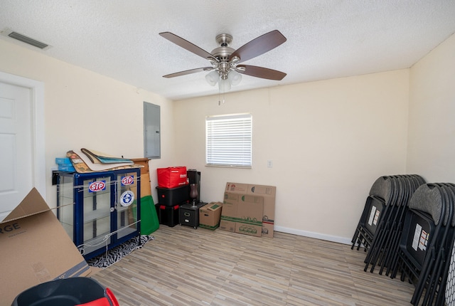 recreation room with ceiling fan, a textured ceiling, and hardwood / wood-style flooring