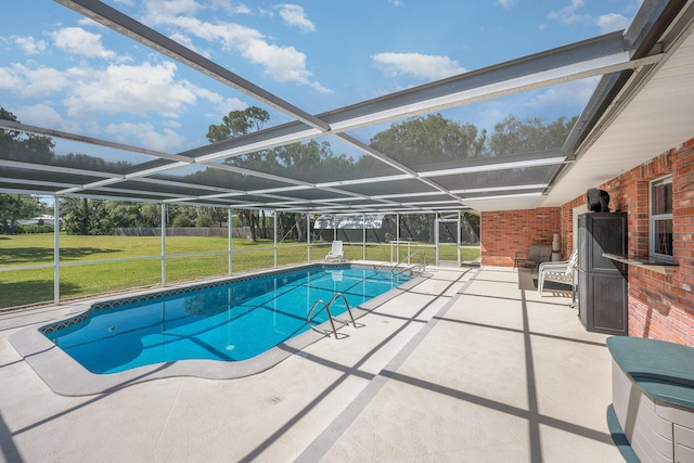 view of swimming pool with a yard, glass enclosure, and a patio