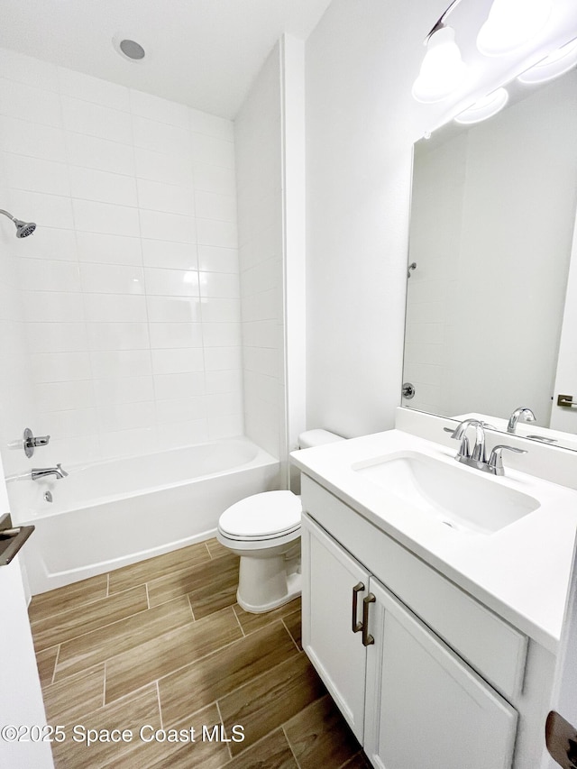 full bathroom with shower / washtub combination, wood finish floors, vanity, and toilet