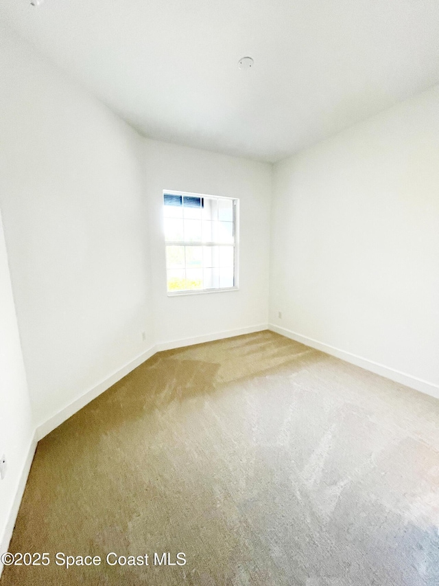 carpeted spare room featuring baseboards