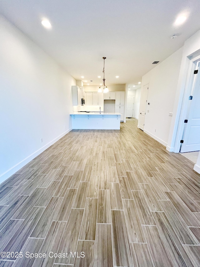 unfurnished living room featuring wood finish floors, recessed lighting, visible vents, and baseboards