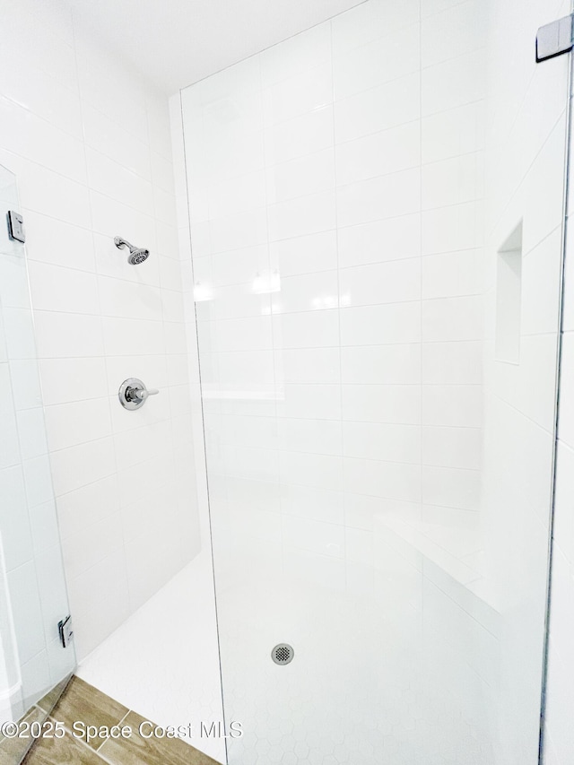 full bathroom with tiled shower and wood finished floors