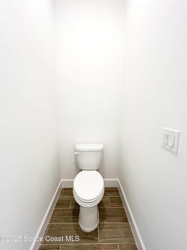 bathroom with toilet, baseboards, and wood finish floors