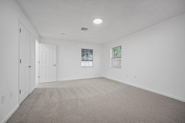 carpeted empty room with a textured ceiling