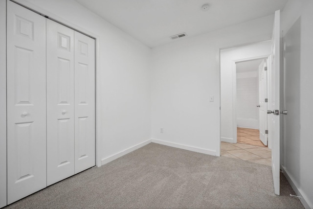 unfurnished bedroom with a closet and light colored carpet