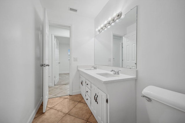 bathroom with double sink vanity, toilet, and tile patterned floors