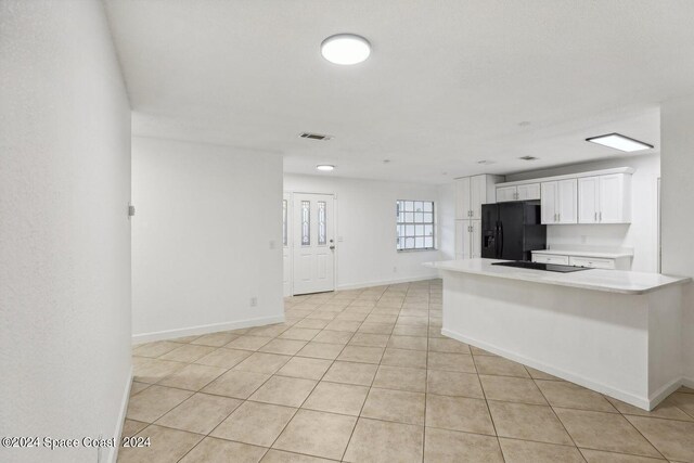 kitchen with white cabinets, black appliances, and light tile patterned floors