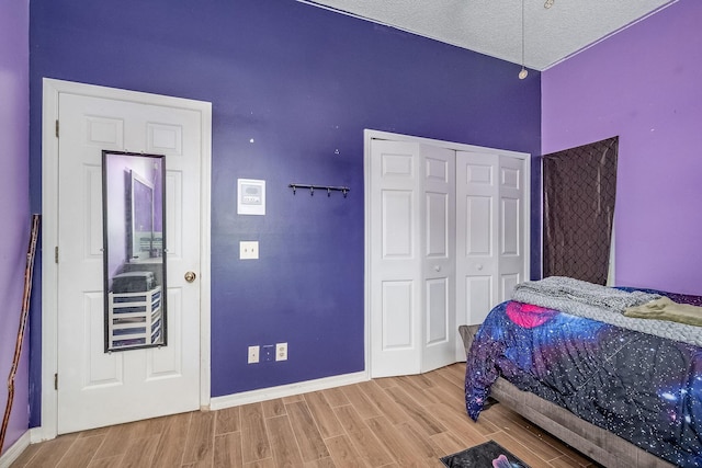 bedroom with a closet, light hardwood / wood-style floors, and a textured ceiling