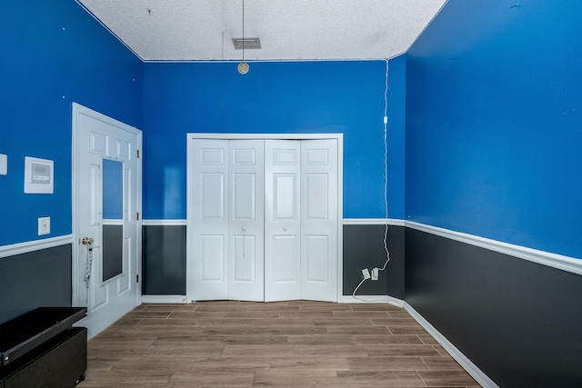 unfurnished bedroom featuring hardwood / wood-style floors, a textured ceiling, and a closet