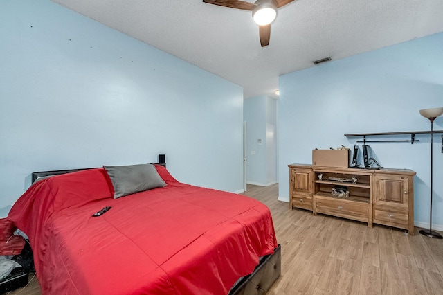 bedroom featuring ceiling fan, hardwood / wood-style floors, and a textured ceiling