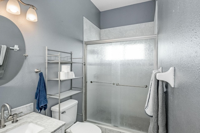 bathroom with vanity, toilet, and a shower with door