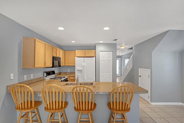 kitchen with a kitchen breakfast bar, kitchen peninsula, white refrigerator with ice dispenser, and stove