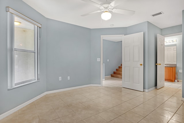 tiled empty room featuring ceiling fan