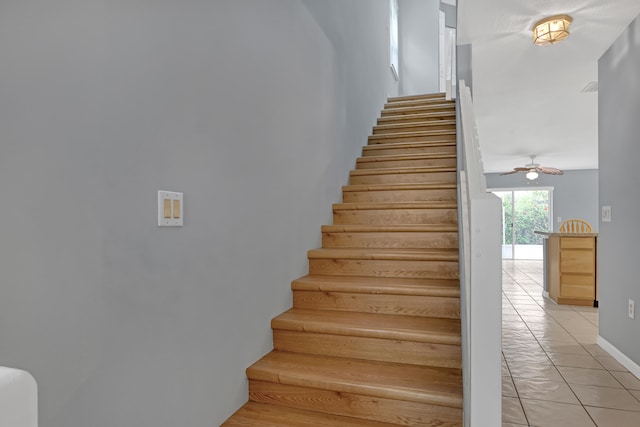 staircase featuring ceiling fan and light tile flooring