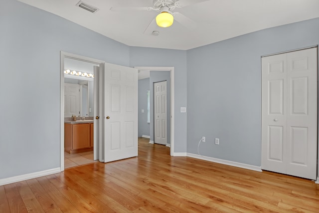 unfurnished bedroom with ceiling fan, a closet, light wood-type flooring, and ensuite bathroom