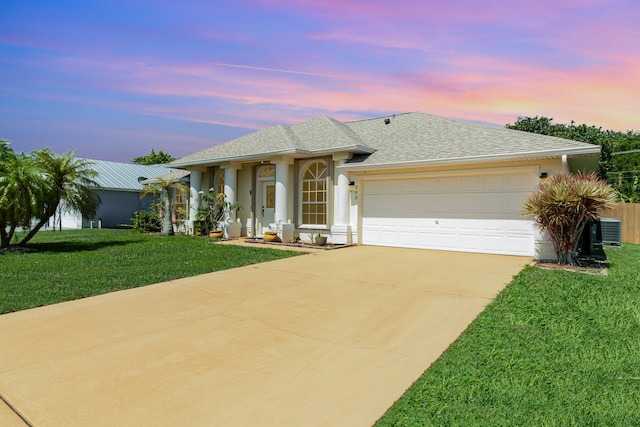 ranch-style house with a yard, cooling unit, and a garage