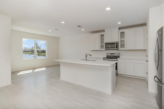 kitchen featuring white cabinets, sink, stainless steel appliances, and a kitchen island with sink