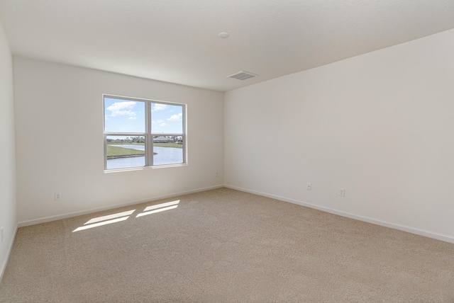 spare room with a water view and light colored carpet