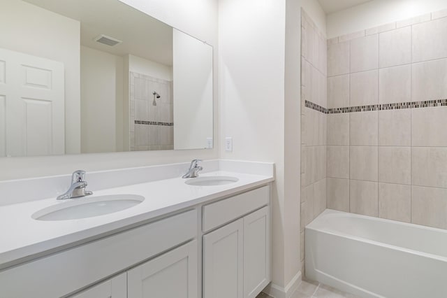 bathroom with tile patterned flooring, vanity, and tiled shower / bath