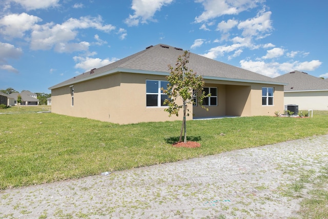 rear view of property featuring a yard and central AC unit