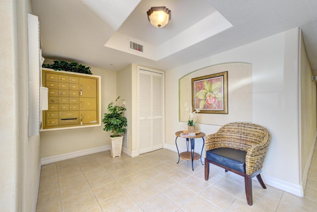 sitting room featuring a raised ceiling and light tile patterned floors