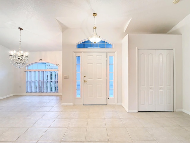 tiled foyer entrance featuring lofted ceiling and a chandelier