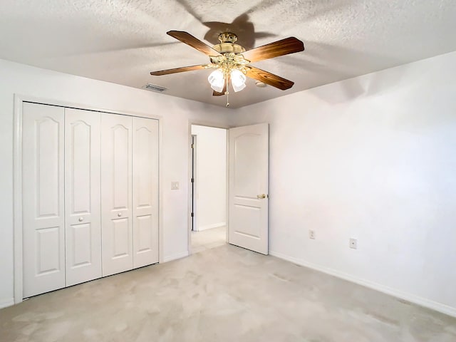 unfurnished bedroom with ceiling fan, light carpet, a textured ceiling, and a closet