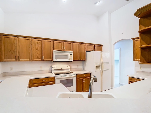 kitchen featuring sink, white appliances, and a towering ceiling