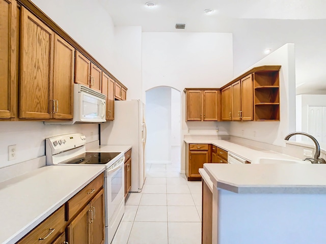 kitchen featuring light tile patterned flooring, sink, kitchen peninsula, a towering ceiling, and white appliances