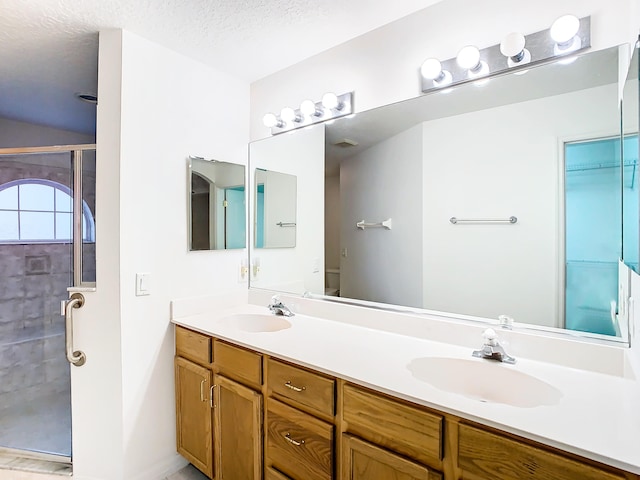 bathroom with vanity, a textured ceiling, and a shower