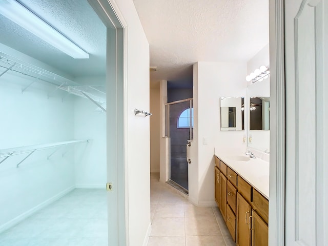 bathroom with tile patterned flooring, vanity, a textured ceiling, and walk in shower